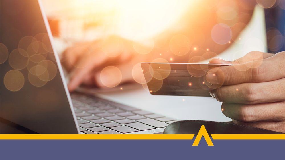 Osoba trzymająca kartę płatniczą przy laptopie podczas płatności online